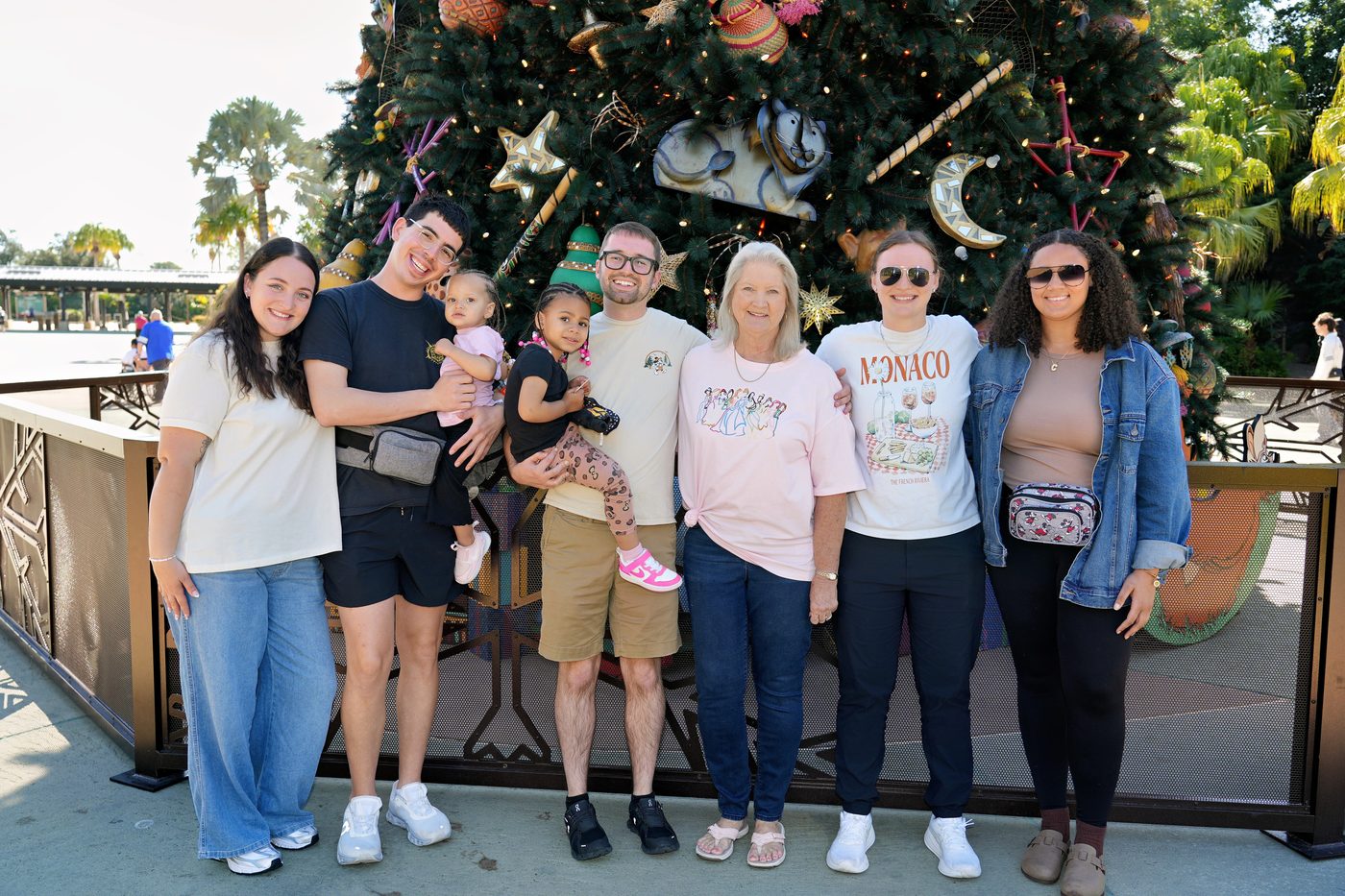 Family standing in front of a holiday tree at Disney